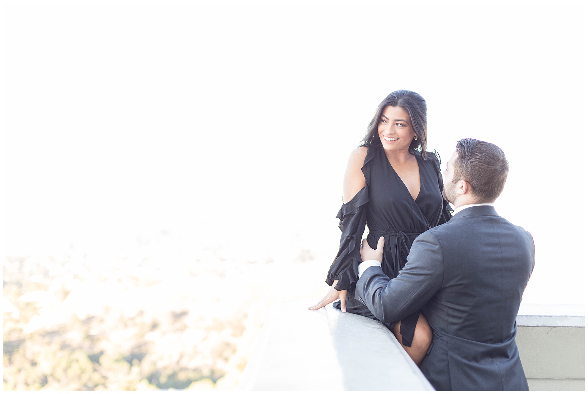 engaged couple overlooking the hollywood skyline on a balcony