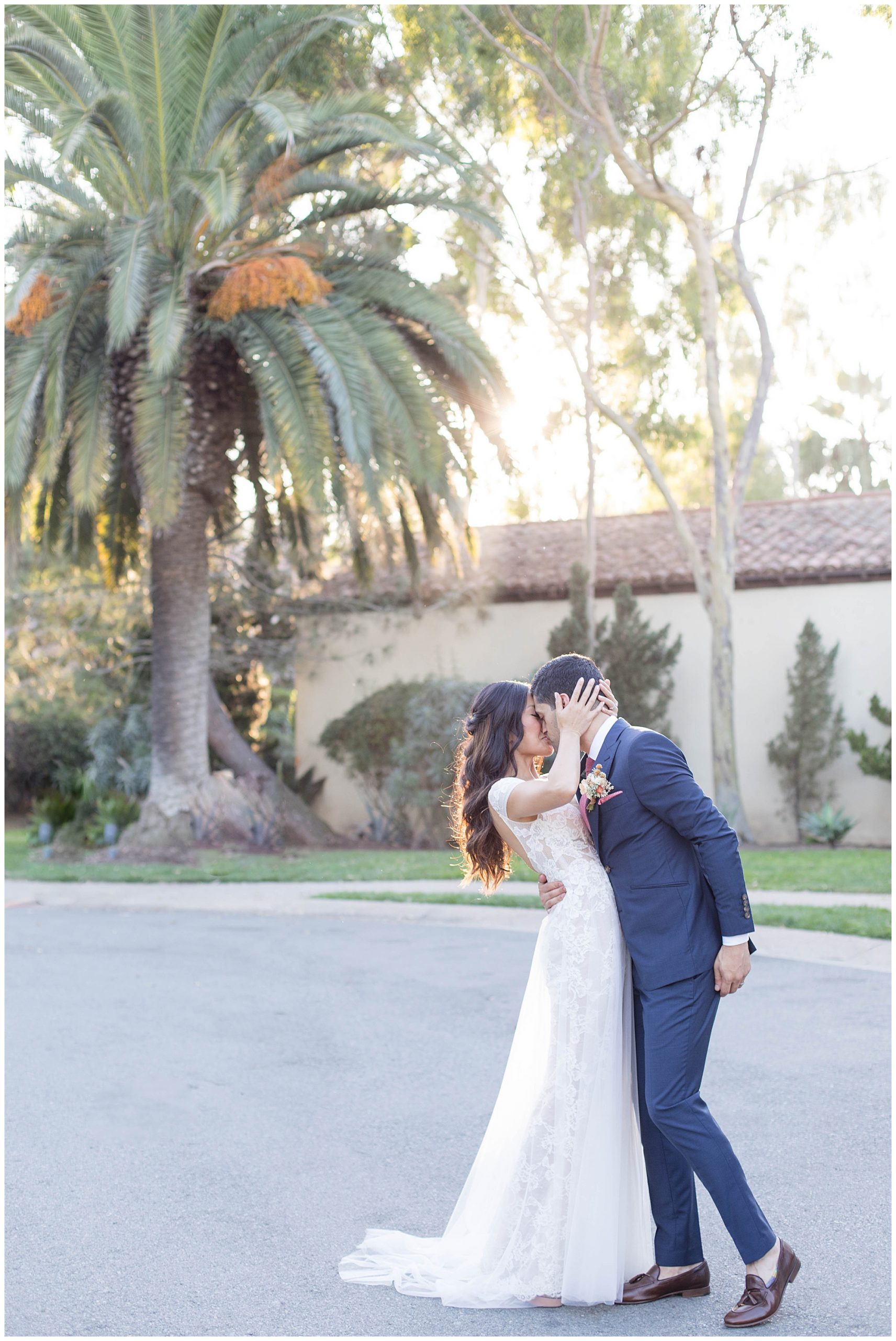 bride and groom kissing in front of a palm tree