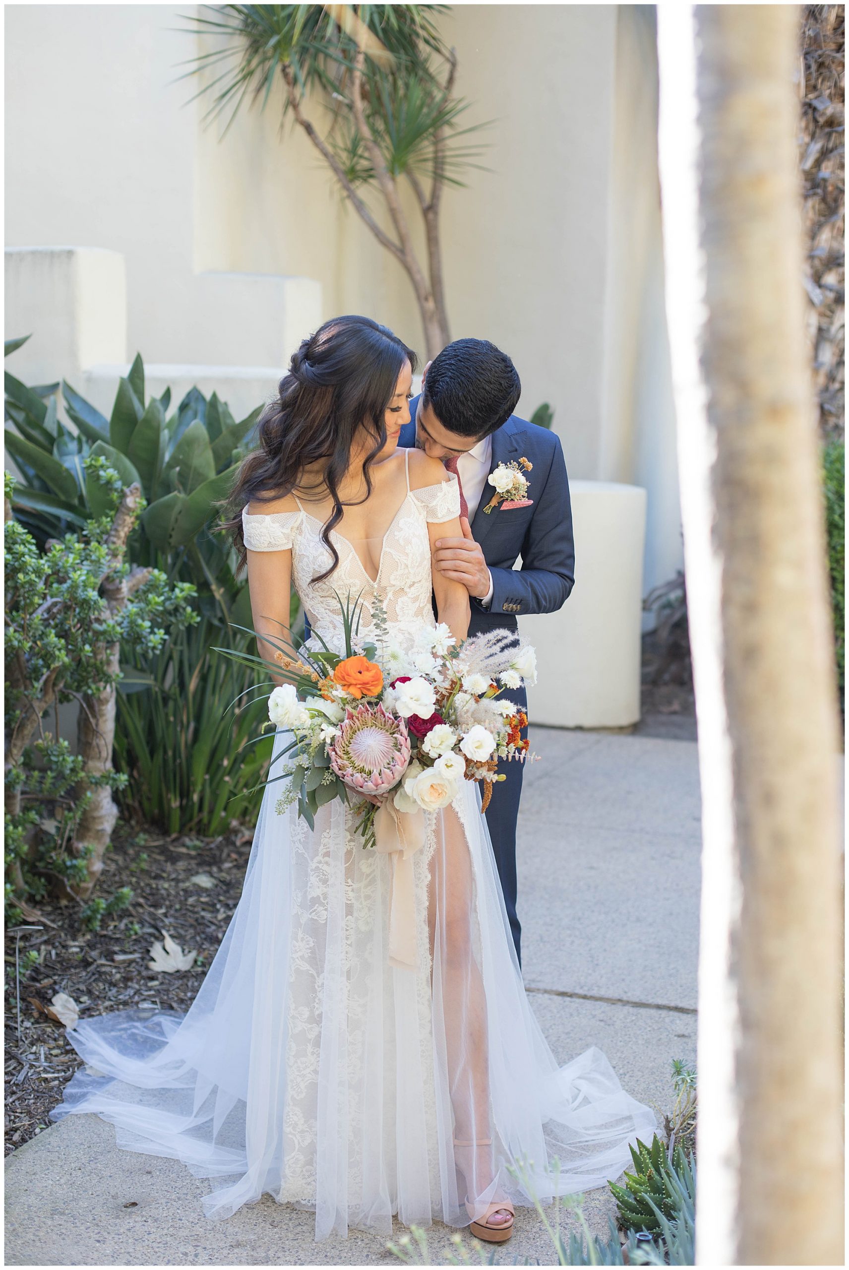 groom kissing his bride on her shoulder at estancia la jolla wedding