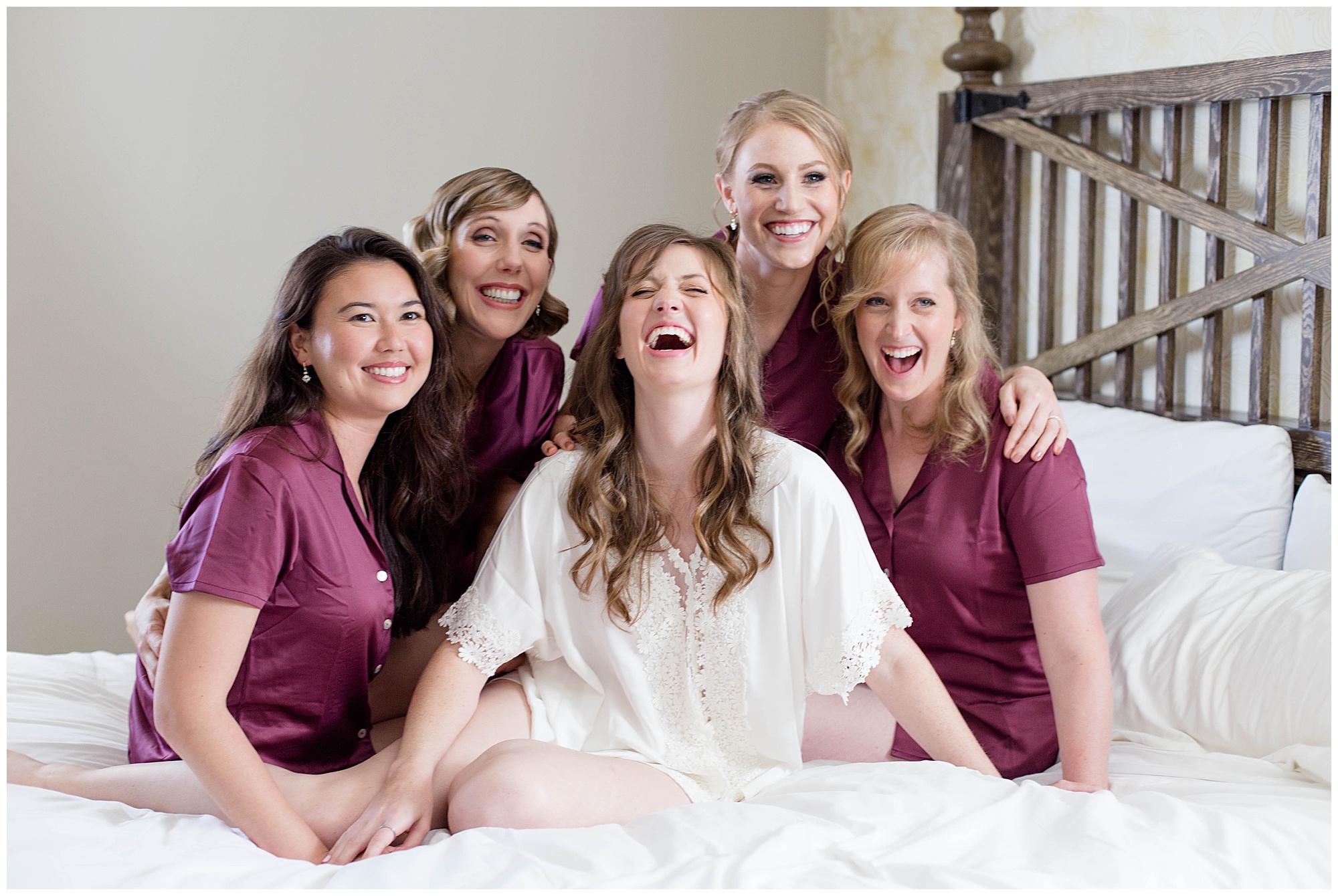 bride with her bridesmaids laughing in bed