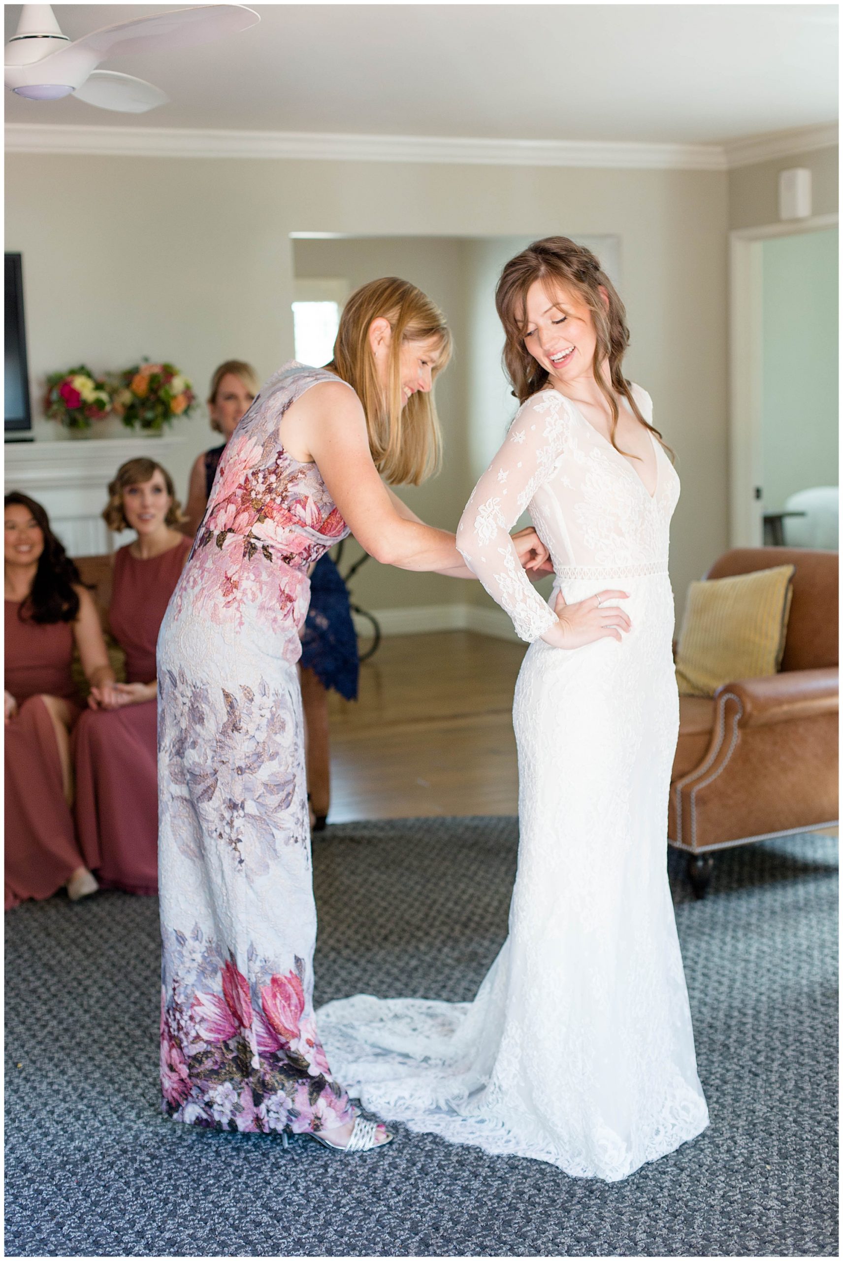 bride smiling as she is getting into her wedding dress