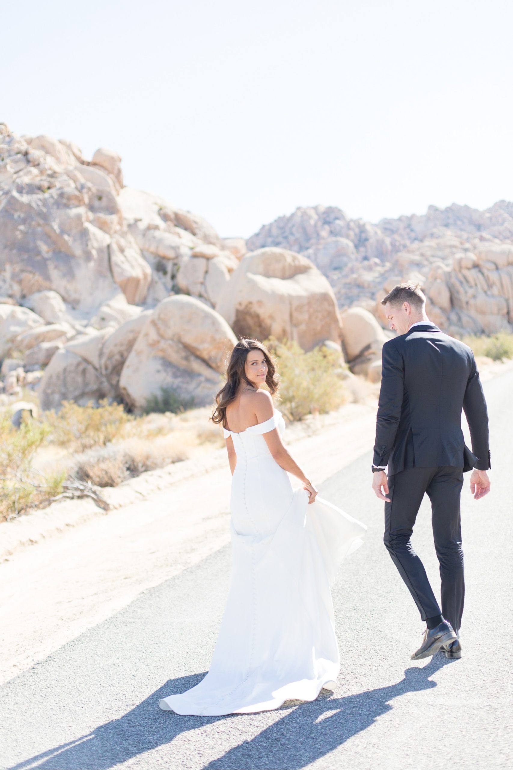 bride and groom walking down road in joshua tree