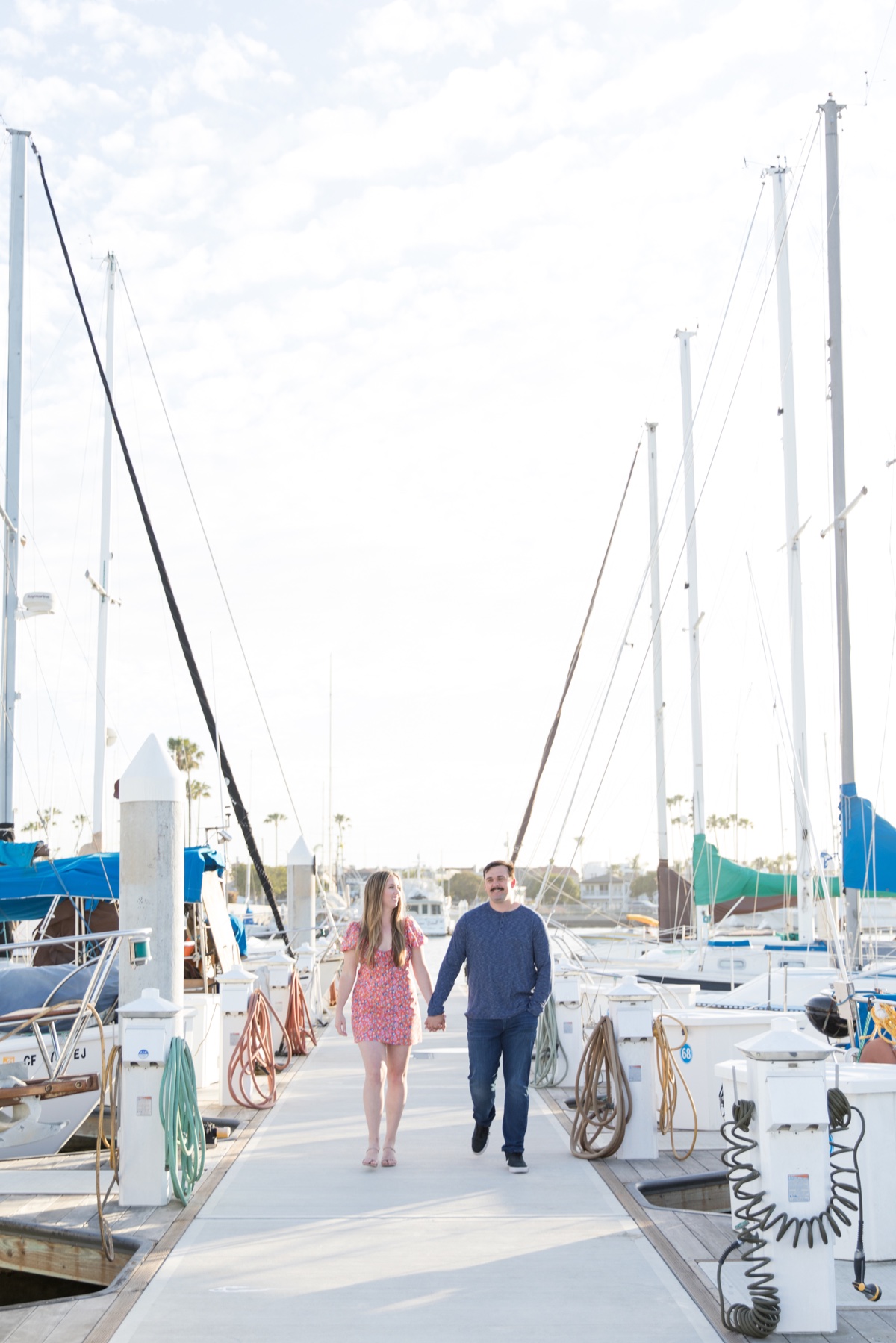 engaged couple walking on a dock in marina Alamitos bay