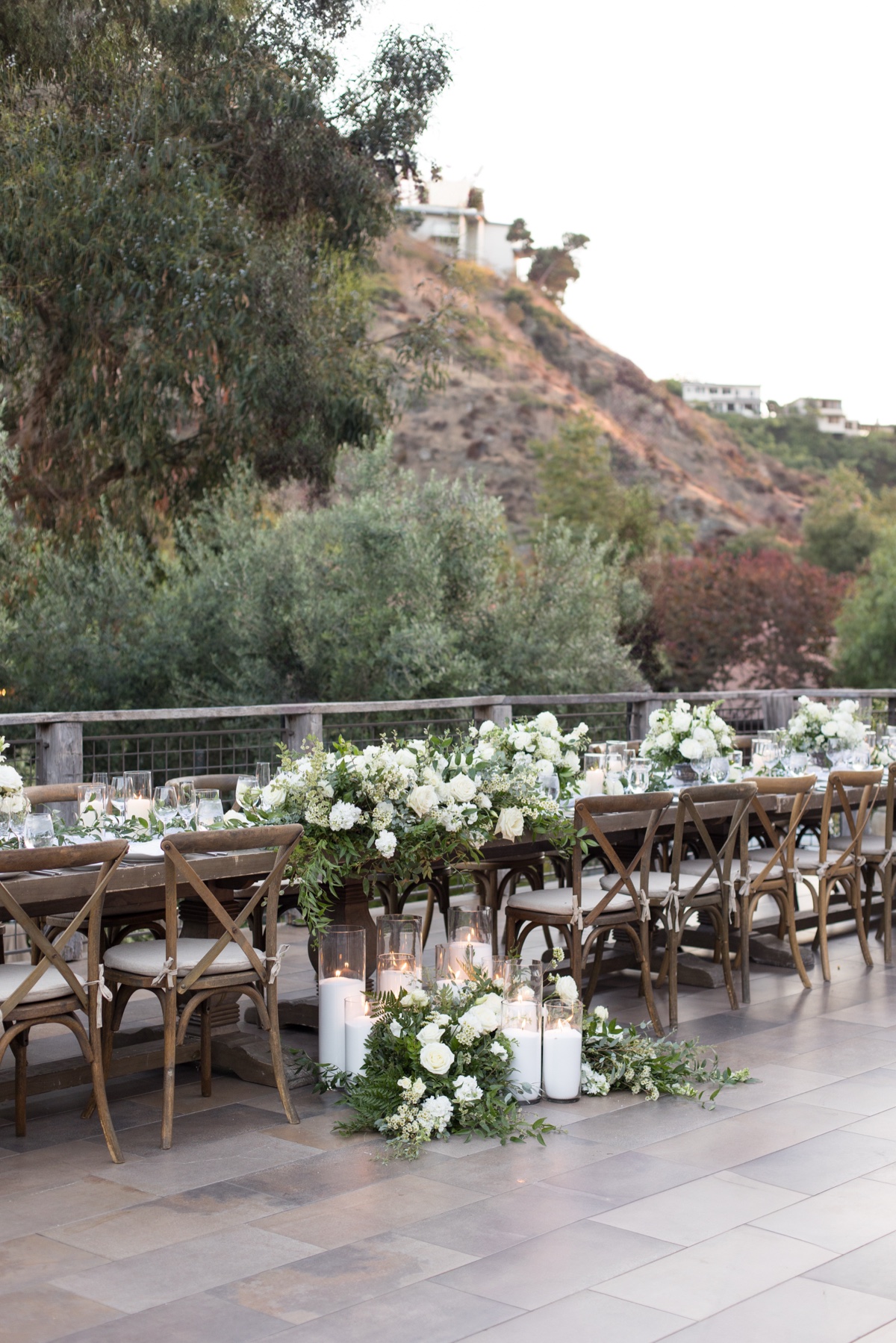 Elegant outdoor wedding reception at The Ranch at Laguna Beach featuring white floral centerpieces, candles, and wooden chairs