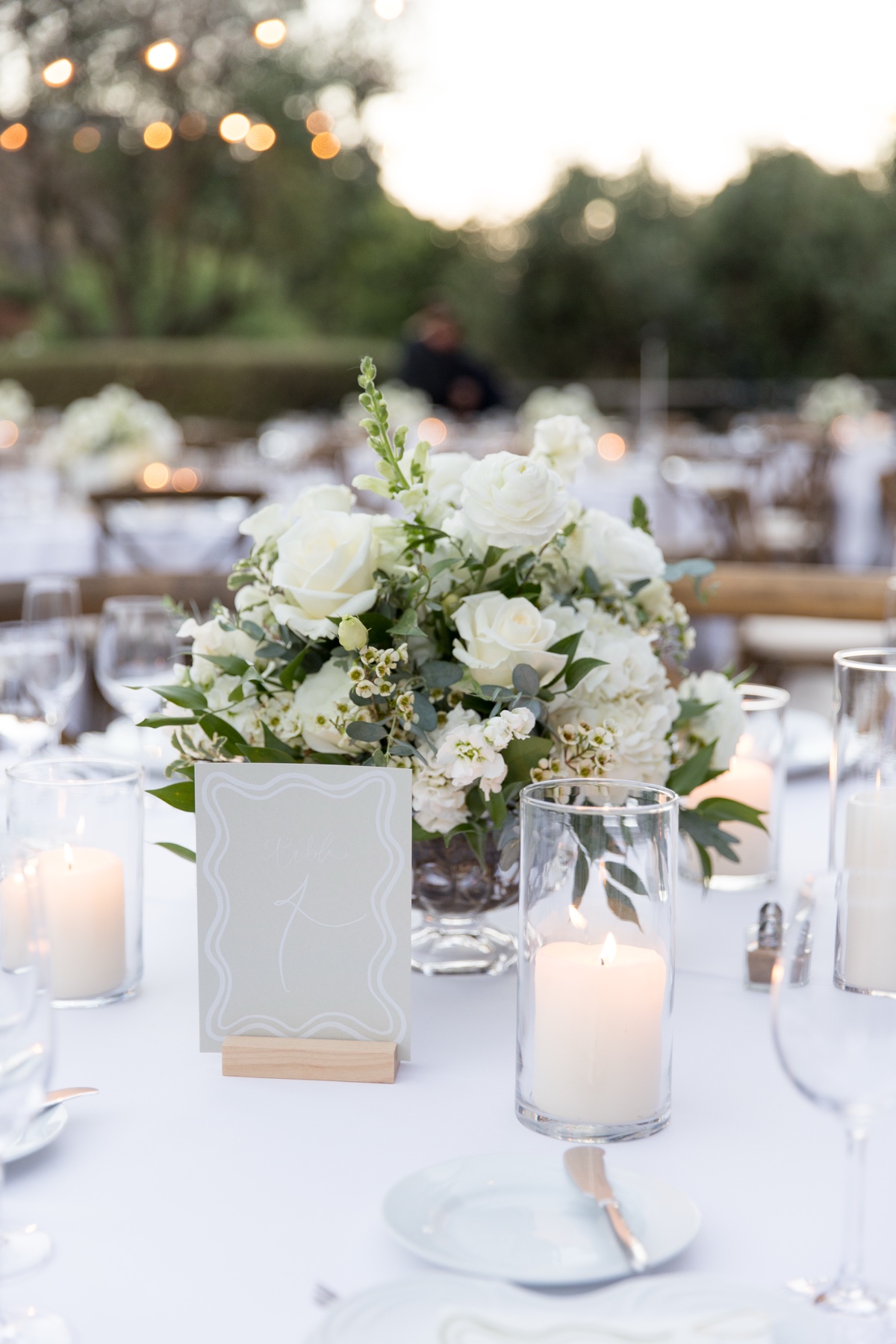 Elegant outdoor wedding reception at The Ranch at Laguna Beach featuring white floral centerpieces, candles, and wooden chairs