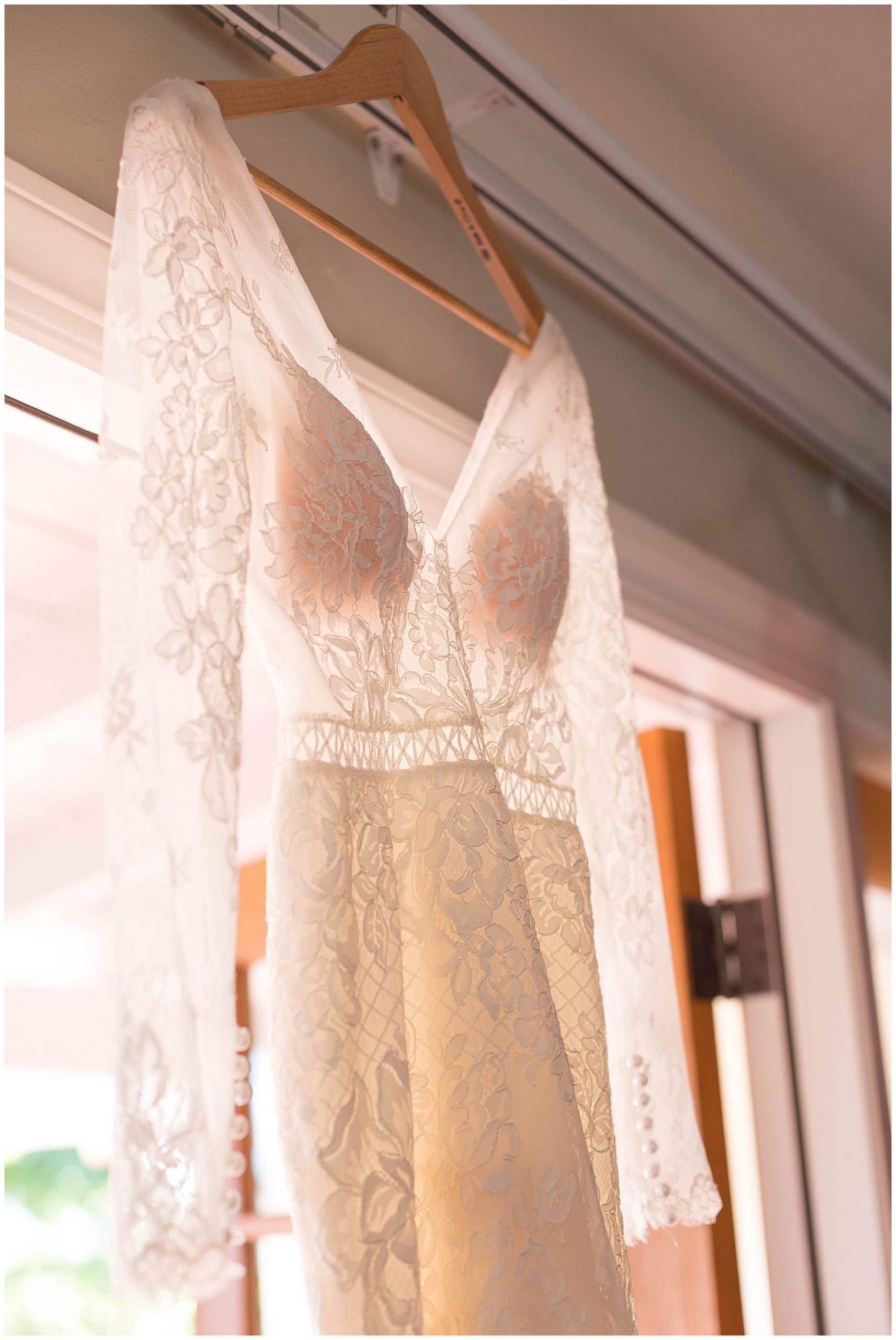 long sleeve lace wedding dress hanging in door