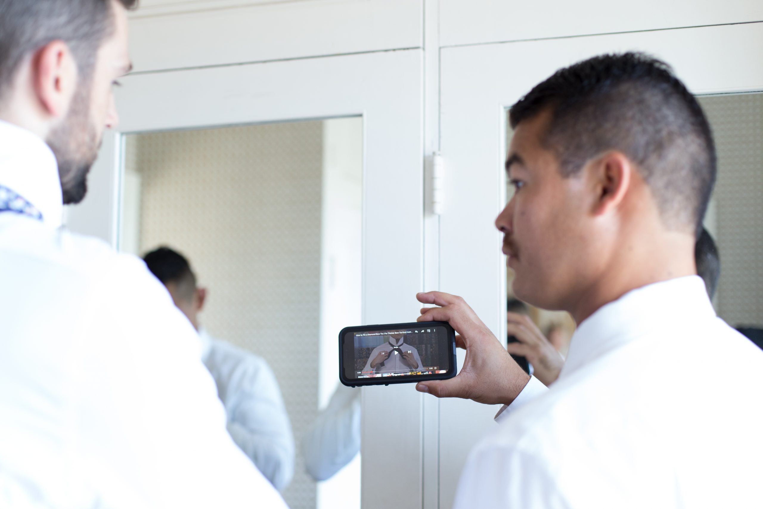 groomsmen looking up how to tie a bowtie on youtube