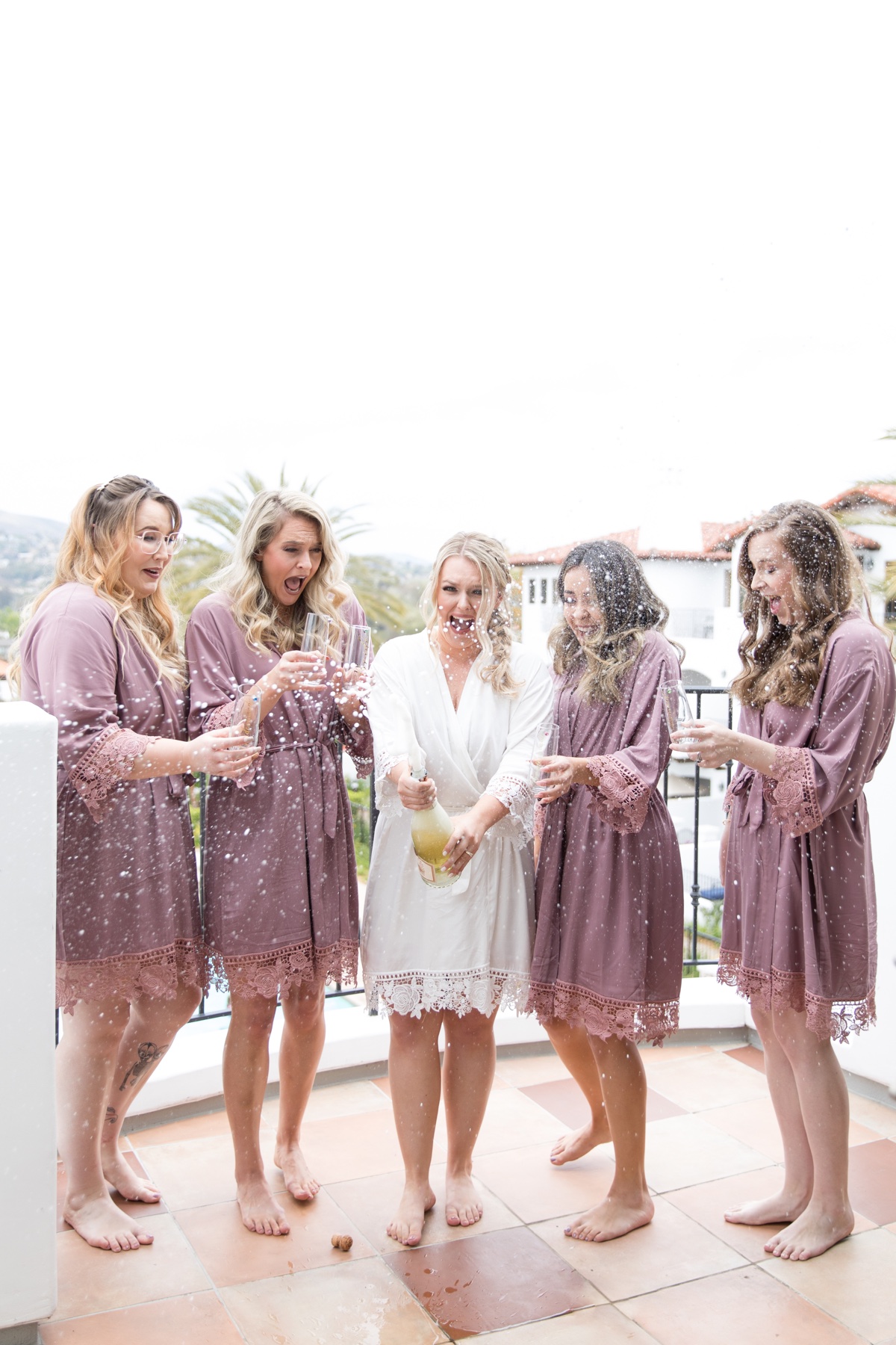 bridesmaids popping champagne on wedding day